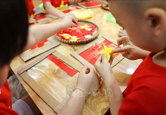 Chỉ bằng những nguyên vật liệu đơn giản, với keo dán trẻ đã tạo ra lá cờ Tổ quốc xinh xắn. Ảnh: Thanh Tùng - TTXVN   