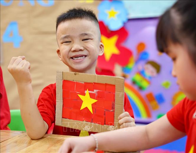 Trẻ thật vui và tự hào khi hoàn thành sản phẩm là lá cờ Tổ quốc của mình. Ảnh: Thanh Tùng - TTXVN   