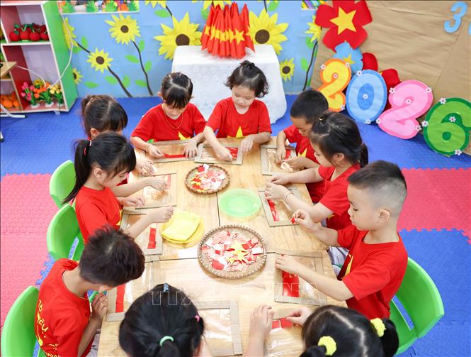 Chỉ bằng những nguyên vật liệu đơn giản, với keo dán trẻ đã tạo ra lá cờ Tổ quốc xinh xắn. Ảnh: Thanh Tùng - TTXVN   