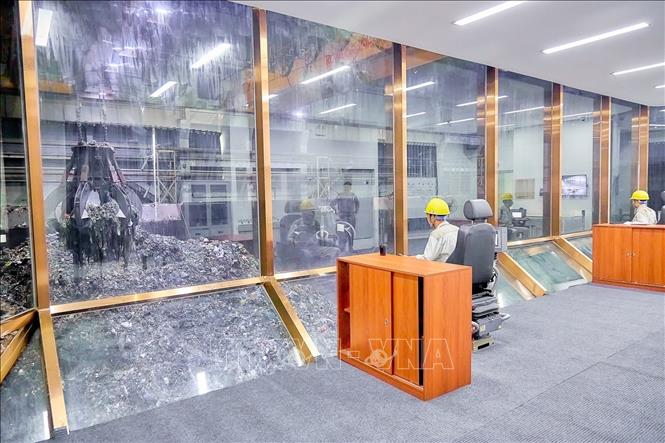 Cánh tay cơ khí với gàu múc khổng lồ đảo, trộn và cấp rác vào lò đốt - mắt xích quan trọng giúp duy trì công suất xử lý hàng nghìn tấn rác mỗi ngày. Ảnh: Trung Nguyên - TTXVN