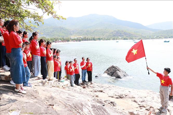 Học sinh trên địa bàn tỉnh Khánh Hoà về với địa chỉ đỏ thực hiện nghi thức chào cờ tại Di tích lịch sử-văn hóa Quốc gia - Điạ điểm lưu niệm sự kiện Tàu C235. Ảnh: Phan Sáu - TTXVN