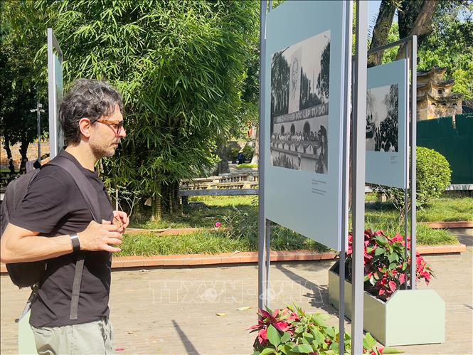 Du khách quốc tế chăm chú thưởng lãm ảnh tại triển lãm ảnh tư liệu với chủ đề “Âm vang ngày mới” tại Khu nhà hầm D67 - Hoàng thành Thăng Long. Ảnh: Tuyết Mai - TTXVN 