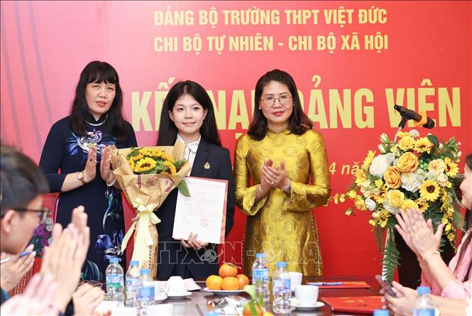 Phó Bí thư thường trực Đảng ủy phường Cửa Nam Phạm Thị Thu Thủy cùng Bí thư Đảng ủy, Hiệu trưởng Trường THPT Việt Đức Nguyễn Bội Quỳnh trao Quyết định kết nạp Đảng cho học sinh. Ảnh: Thanh Tùng – TTXVN