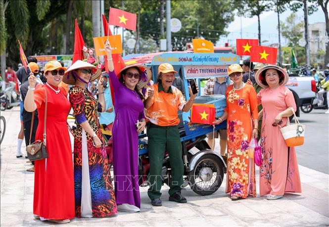 Người dân trong trang phục áo dài rực rỡ, tay cầm cờ Tổ quốc, rạng rỡ hòa mình vào không khí kỷ niệm ngày 30/4 trên đường phố Tây Ninh, lan tỏa niềm tự hào dân tộc và tình yêu quê hương. Ảnh: Giang Phương - TTXVN