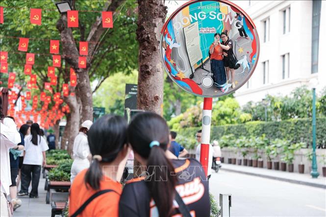 Du khách chụp ảnh lưu niệm tại khu vực check-in ngoài trời của di tích Nhà tù Hoả Lò. Ảnh: Phạm Tuấn Anh - TTXVN