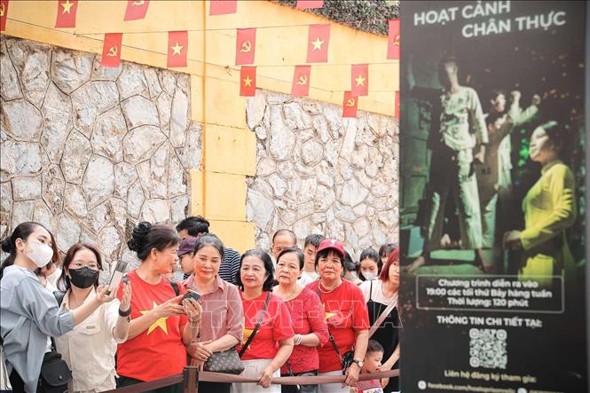 Du khách chụp ảnh lưu niệm trong lúc xếp hàng chờ đến lượt vào tham quan di tích Nhà tù Hoả Lò. Ảnh: Phạm Tuấn Anh - TTXVN