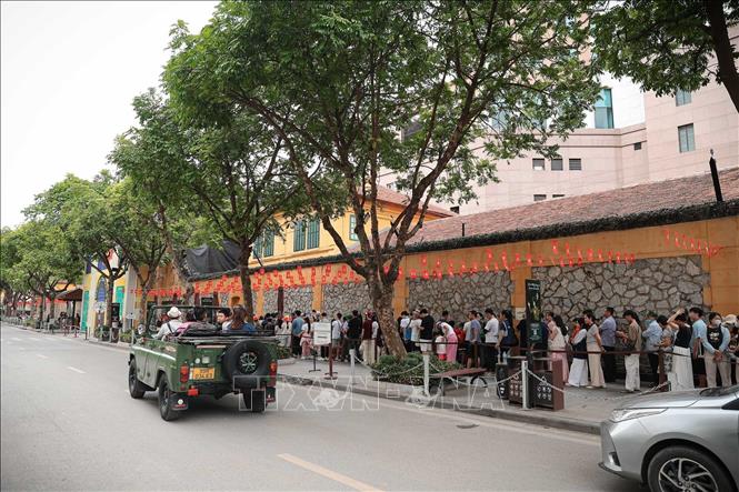 Nhiều gia đình, nhóm du khách xếp hàng dài chờ đến lượt vào tham quan di tích Nhà tù Hoả Lò. Ảnh: Phạm Tuấn Anh - TTXVN