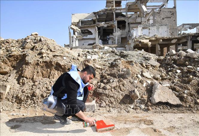 Nhân viên dò thiết bị nổ giữa đống đổ nát của những toà nhà ở Jobar, Syria. Ảnh: THX/TTXVN