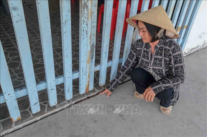 Bà Lê Thị Hoàng Mai (ấp Phú Tây, xã Nhơn Mỹ) chỉ những vết nứt lớn xuất hiện ngay cửa nhà sau khi con đường trước nhà bà Mai bị sụp xuống sông. Ảnh: Thanh Liêm - TTXVN