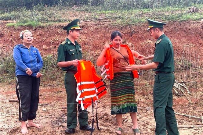 Cán bộ, chiến sĩ Đồn Biên phòng Thông Thụ trao tặng và hướng dẫn cách sử dụng áo phao đúng cách người dân sinh sống quanh khu vực lòng hồ Thủy điện Hủa Na; tuyên truyền nâng cao ý thức, thực hiện nghiêm việc đảm bảo an toàn giao thông đường thủy trên lòng hồ. Ảnh: TTXVN phát 