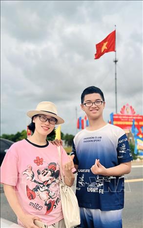 Du khách thích thú chụp ảnh lưu niệm tại cột cờ giới tuyến tại Khu di tích Quốc gia đặc biệt Đôi bờ Hiền Lương - Bến Hải. Ảnh: Nguyên Linh-TTXVN