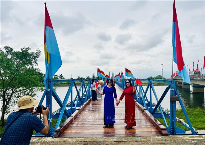 Du khách thích thú chụp ảnh lưu niệm tại cầu Hiền Lương. Ảnh: Nguyên Linh – TTXVN