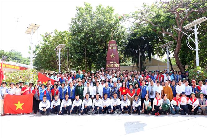 Đoàn công tác số 12 chụp hình lưu niệm trước cột mốc đảo Sinh Tồn. Ảnh: Tiến Lực - TTXVN