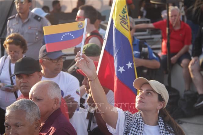 Một phụ nữ giơ cao lá cờ Venezuela, thể hiện tinh thần sát cánh cùng Cuba, trong cuộc mít tinh ở thủ đô La Habana, sáng 1/5/2026 (giờ địa phương). Ảnh: Ngọc Duy - PV TTXVN tại Cuba