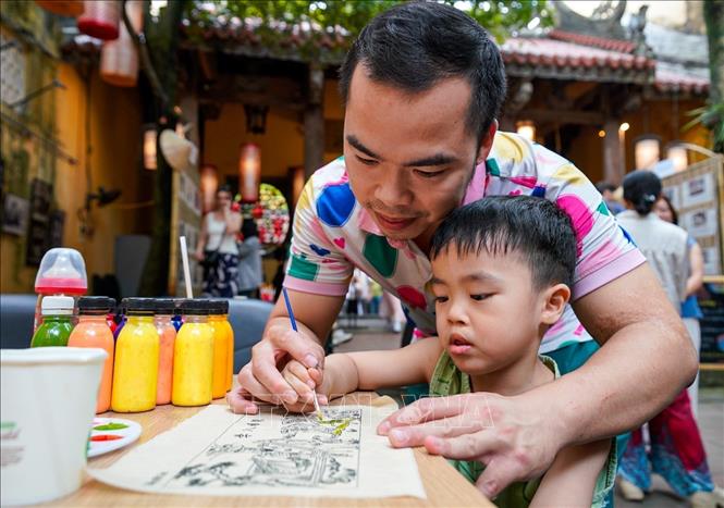 Người dân trải nghiệm thực hiện tác phẩm tranh. Ảnh: Khánh Hoà - TTXVN