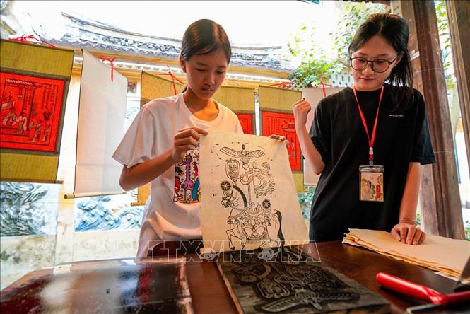 Người dân trải nghiệm in mộc bản. Ảnh: Khánh Hoà - TTXVN