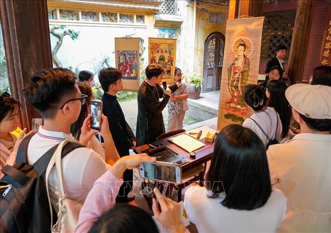 Người dân và du khách nghe giới thiệu về tranh Hàng Trống. Ảnh: Khánh Hoà - TTXVN