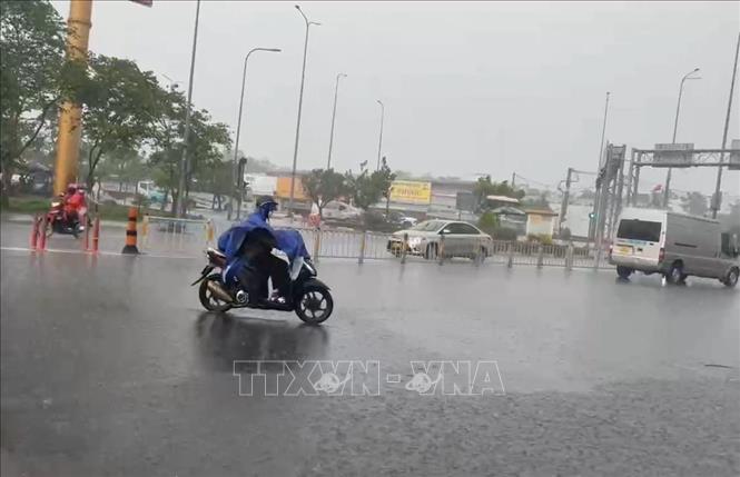 Người dân di chuyển trong cơn mưa trên đường Võ Văn Kiệt, phường An Lạc. Ảnh: Hồng Đạt - TTXVN