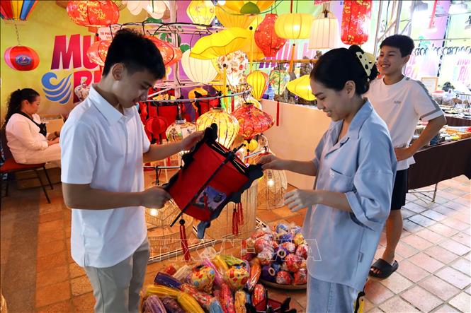 Giới trẻ hào hứng tìm hiểu về sản phẩm làng nghề truyền thống đèn lồng Hội An. Ảnh: Trần Lê Lâm - TTXVN 