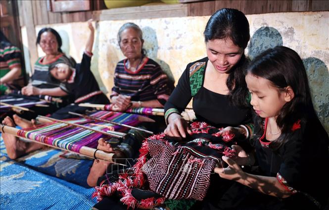 Hướng dẫn các cháu nhỏ làm vải thổ cẩm. Ảnh: Trần Việt - TTXVN