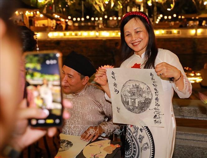 Người dân và du khách trải nghiệm in tranh và xin chữ. Ảnh: Khánh Hoà - TTXVN