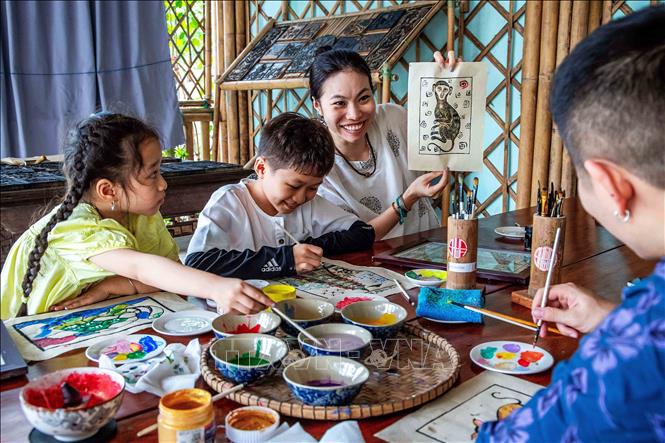 Visitors enjoy creating a Sinh village's folk painting. VNA Photo: Vân Chi/Photo by courtesy