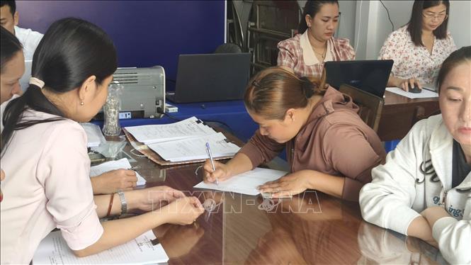 Cán bộ, công chức của Tổ hành chính lưu động phường Vĩnh Trạch giúp người dân kê khai, làm thủ tục theo quy định. Ảnh: Tuấn Kiệt - TTXVN