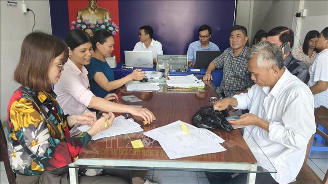 Cán bộ, công chức của Tổ hành chính lưu động phường Vĩnh Trạch tiếp, hỗ trợ công dân soạn các giấy tờ cần thiết để hoàn thiện hồ sơ hành chính. Ảnh: Tuấn Kiệt - TTXVN
