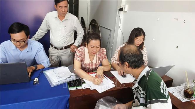 Cán bộ bộ phận đất đai viết giấy tay hướng dẫn người dân từng bước để chuẩn bị hồ sơ làm thủ tục hành chính. Ảnh: Tuấn Kiệt – TTXVN