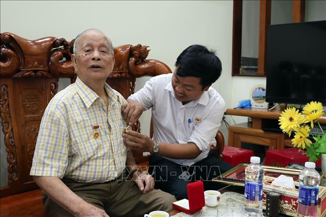 Lãnh đạo Hội Cựu chiến binh phường Hội An Tây gắn lại những những tấm Huân, Huy chương kháng chiến cao quý lên ngực áo của cựu chiến binh Ngô Văn Quy. Ảnh: Đỗ Trưởng – TTXVN