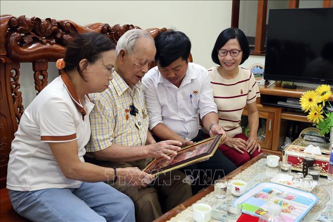 Cựu chiến binh Ngô Văn Quy (giữa) cùng với người thân và lãnh đạo Hội Cựu chiến binh phường Hội An Tây xem lại những tấm Huân, Huy chương kháng chiến cao quý. Ảnh: Đỗ Trưởng – TTXVN