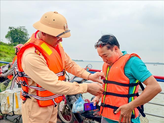 Việc hỗ trợ người dân mặc áo phao được lực lượng chức năng duy trì thường xuyên nhằm nâng cao ý thức bảo đảm an toàn giao thông đường thủy. Ảnh: Trung Nguyên - TTXVN