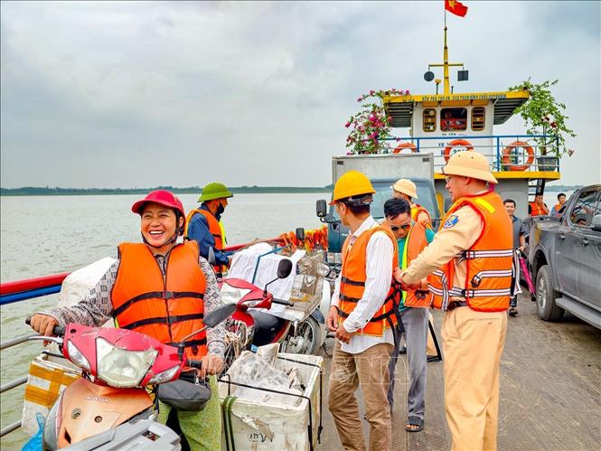 Đội Cảnh sát đường thủy số 1 trực tiếp nhắc nhở hành khách mặc áo phao trước khi xuống phương tiện qua sông. Ảnh: Trung Nguyên - TTXVN