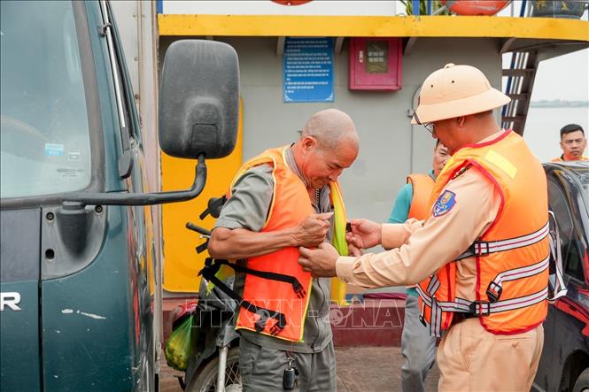 Việc hỗ trợ người dân mặc áo phao được lực lượng chức năng duy trì thường xuyên nhằm nâng cao ý thức bảo đảm an toàn giao thông đường thủy. Ảnh: Trung Nguyên - TTXVN