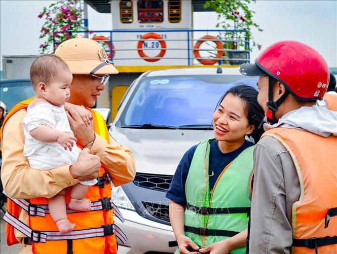 Hình ảnh gần gũi của cán bộ Cảnh sát đường thủy Hà Nội trong quá trình tuyên truyền, nhắc nhở người dân chấp hành quy định mặc áo phao khi qua sông. Ảnh: Trung Nguyên - TTXVN