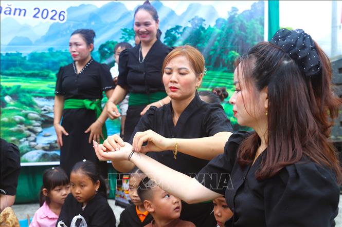Phụ nữ trong trang phục truyền thống của người Ơ Đu đang cột chỉ cổ tay cho nhau trong ngày đầu tiên tổ chức lễ đón tiếng sấm đầu năm. Ảnh: Xuân Tiến - TTXVN 