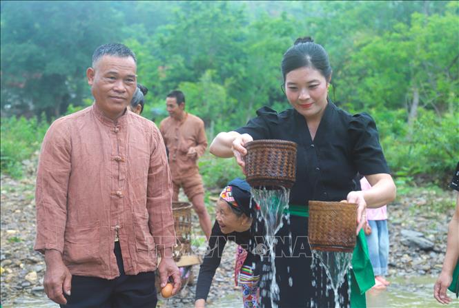 Phụ nữ mang rửa dụng cụ đựng cơm nếp của gia đình trên “suối thiêng” Nậm Ngân trong ngày đầu tiên có tiếng sấm. Ảnh: Xuân Tiến - TTXVN 