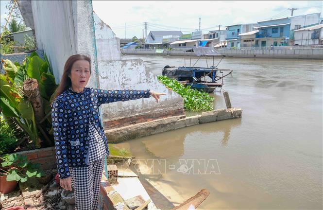 Bà Nguyễn Thị Út (xã Thạnh Hòa) chỉ vị trí căn nhà của bà bị sụp xuống sông Nàng Mau trong vụ sạt lở xảy ra hồi tháng 6/2025. Ảnh: Thanh Liêm - TTXVN