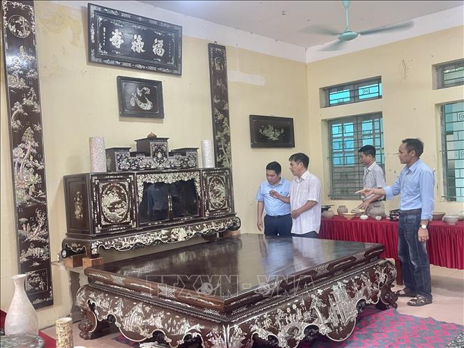 Artisan Vu Van Vinh from Chuyen My introduces to visitors his family’s mother-of-pearl inlaid lacquerware set, including a platform bed, tea cabinet and lacquered horizontal lacquer boards and parallel sentences, valued at over 3 billion VND. Photo: Tuyet Mai – VNA