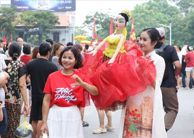 Người dân thích thú chụp hình cùng các con rối. Ảnh: Mạnh Minh - TTXVN