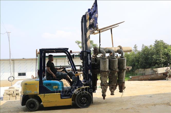 Công nhân tháo dỡ máy móc, trang thiết bị di dời ra khỏi khu vực nhà xưởng tại cơ sở tái chế giấy tại thôn Toàn An, xã Đông Cuông (Lào Cai). Ảnh: Anh Thùy - TTXVN