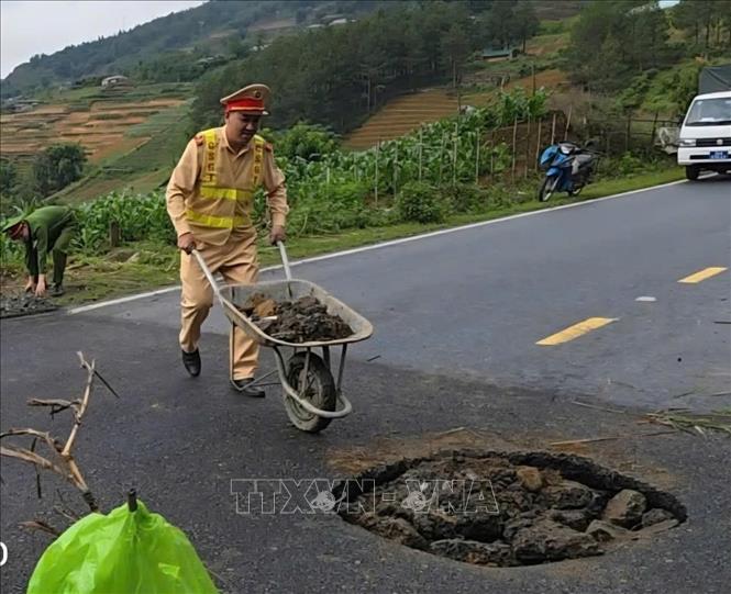 Lực lượng chức năng đặt biển cảnh báo, tiến hành lấp các hố sụt để đảm bảo an toàn. Ảnh: TTXVN phát