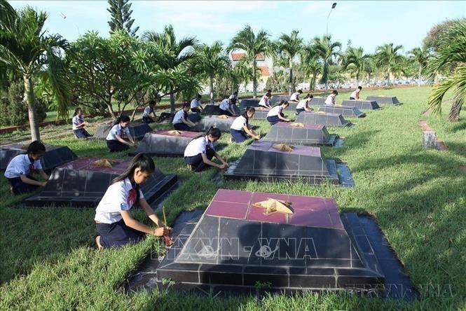 Học sinh trường THCS Trần Hưng Đạo, tỉnh Phú Yên chăm sóc phần mộ liệt sĩ tại Nghĩa trang liệt sĩ Đông Tác. Ảnh: Anh Tuấn - TTXVN
