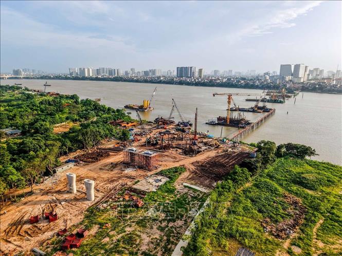 Máy móc và nhân lực của nhà thầu đang tích cực triển khai hạng mục khoan cọc nhồi trên bờ và hạng mục dưới sông. Ảnh: Phạm Tuấn Anh - TTXVN