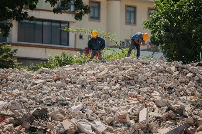 Công nhân thu gom sắt thép, vật liệu còn sót lại sau quá trình phá dỡ công trình. Ảnh: Phạm Tuấn Anh - TTXVN