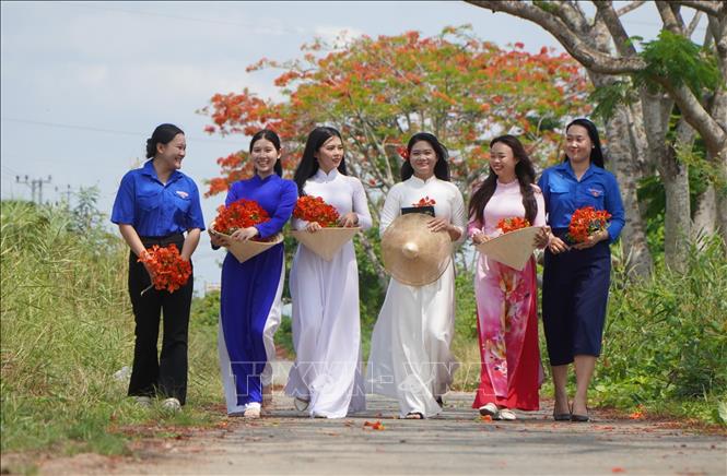 Young girls keeping their memories of youth with phuong vi flowers. VNA Photo: Nhựt An