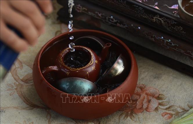 Trước khi pha trà sen, người nghệ nhân sẽ làm rửa sạch và làm nóng ấm chén trà. Ảnh: Văn Dũng-TTXVN