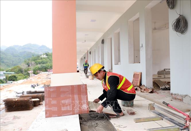 Công nhân lát sàn hành lang và các lớp học. Ảnh: Quý Trung – TTXVN