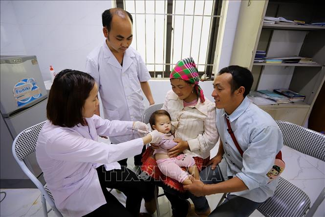 Vợ chồng Anh Thào A Thái (bản Háng Đồng) đua con gái 13 tháng tuổi tiêm chủng tại Trạm Y tế xã Tà Xùa. Ảnh: Trọng Đạt-TTXVN