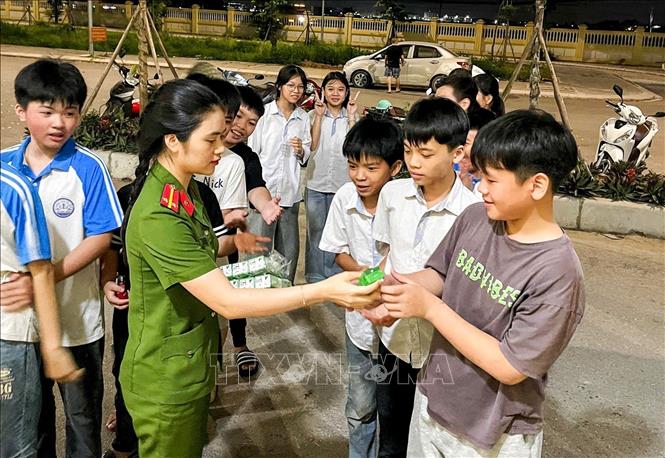 Nữ Công an phường Thuận Thành, phát sữa cho học sinh đến làm CCCD. Ảnh: Danh Lam -TTXVN 